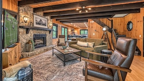 A cozy living room with a stone fireplace, wooden walls, and a comfortable seating area. - Casa Azul - Secluded, Modern, Arcade, Hot Tub, Dogs Welcome! (Blue Ridge)