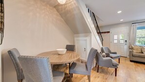 A dining area with a round table, grey upholstered chairs, and a wooden floor.