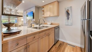 A modern kitchen with wooden cabinets, stainless steel appliances, and a large island with a bowl and glasses.