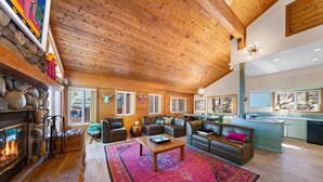 A spacious living room with a stone fireplace, leather sofas, and a colorful rug.