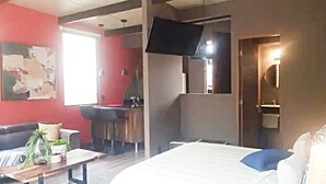 A hotel room with a bed, a desk, a chair, a TV mounted on the wall, and a bathroom with a mirror and sink. - Loft Tree House 1 by Kivoya (Zapopan)