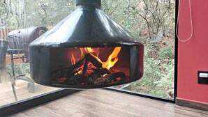 A wood-burning stove in a modern room with a large window overlooking a forest. - Loft Tree House 1 by Kivoya (Zapopan)
