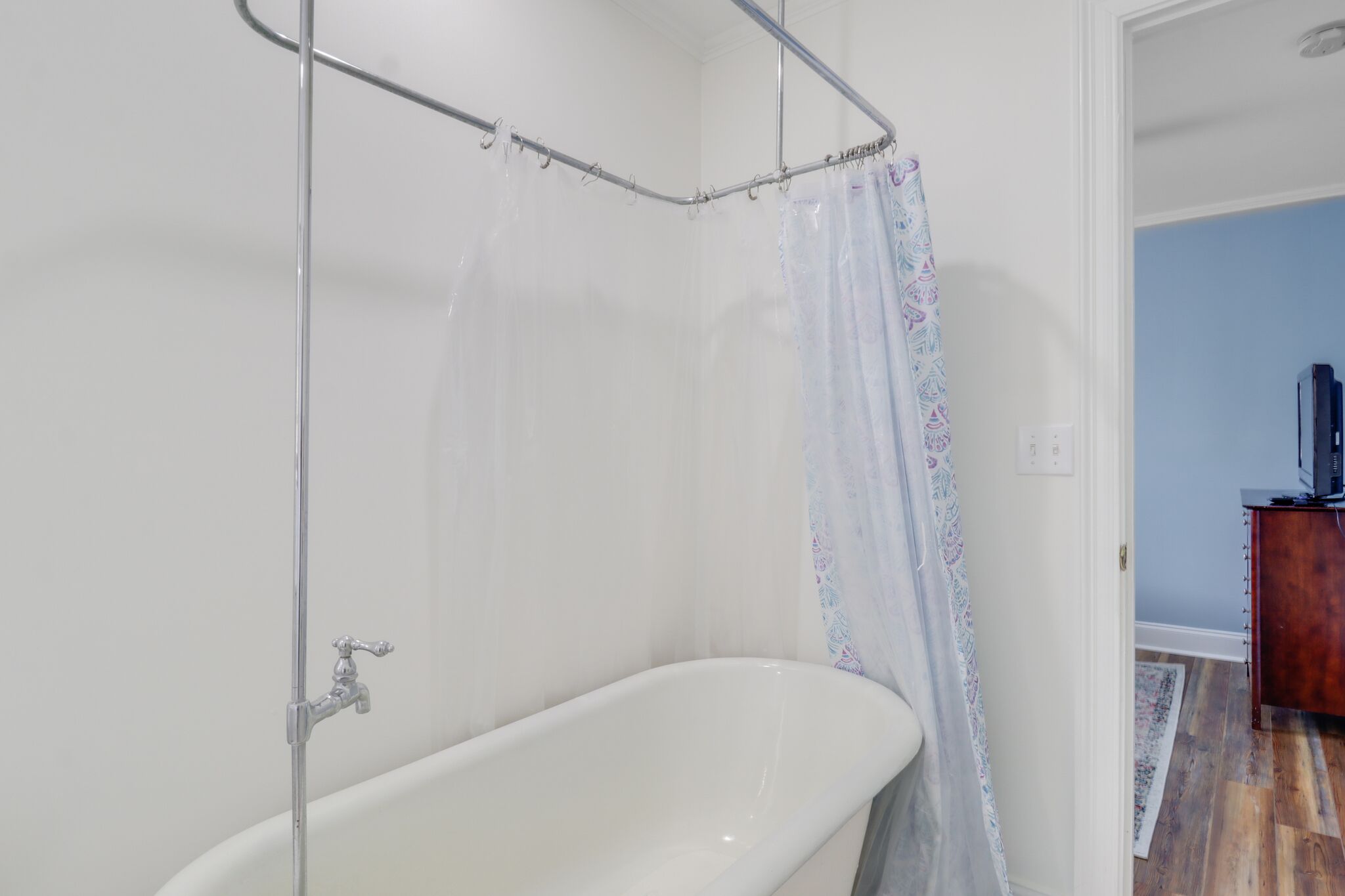 A bathroom with a white bathtub, a shower curtain, and a wooden cabinet.