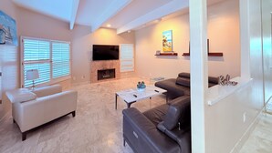 A spacious living room with a fireplace, a flat-screen TV, and a comfortable seating area.