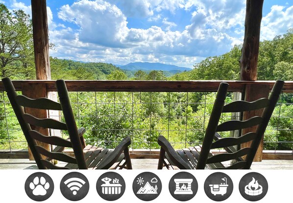 Relax in a serene outdoor seating area with mountain views, featuring two comfortable chairs on a deck with a railing.