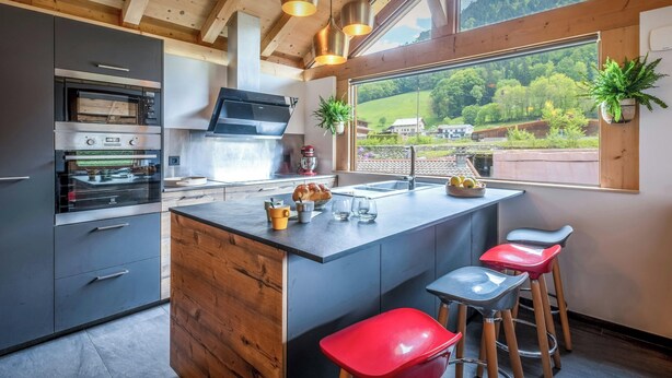 Una cocina moderna con una isla grande, horno empotrado y taburetes de bar.