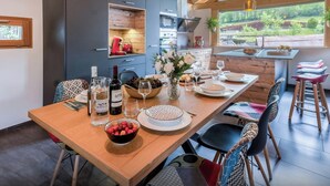 Una cocina moderna con una mesa de madera preparada para comer, un horno empotrado y vistas al exterior.