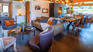 Amplia sala de estar con sofá, sillas, mesa de comedor y zona de cocina.