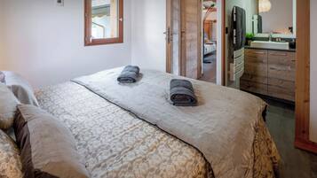 Une chambre à coucher avec un lit, deux serviettes, une fenêtre et une salle de bain visible à travers une porte ouverte.