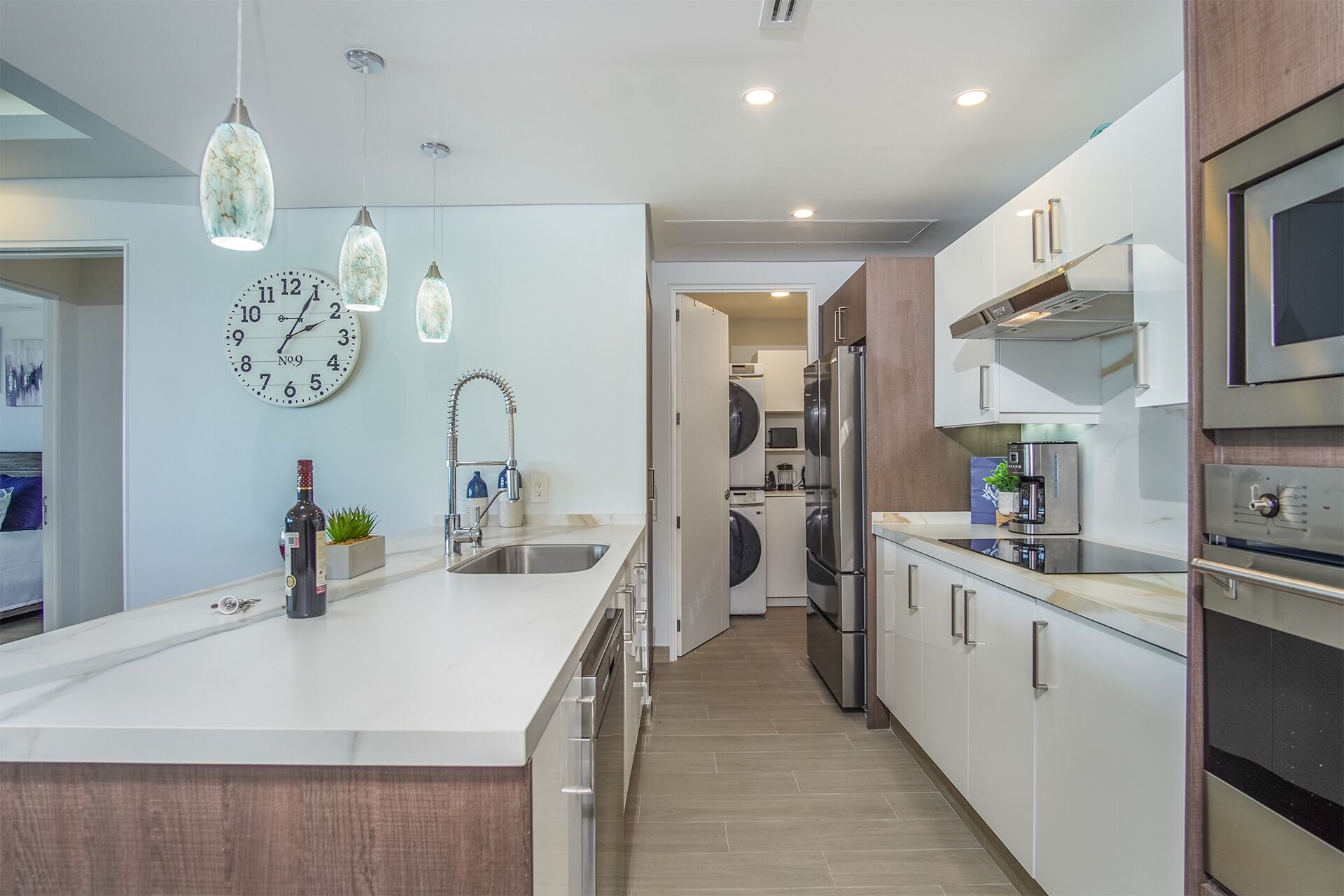 A modern kitchen with a central island, stainless steel appliances, and pendant lighting.