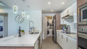 Een moderne keuken met een centraal eiland, roestvrijstalen apparatuur en hanglampen.