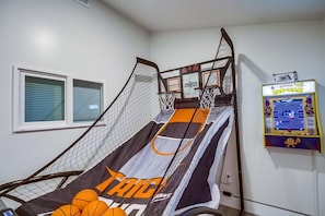 A basketball court with a net, a scoreboard, and a Pac-Man arcade machine.