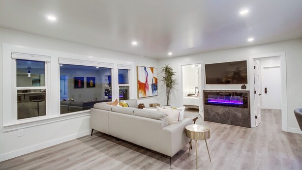 A modern living room with a white sofa, a small round table, and a large window.