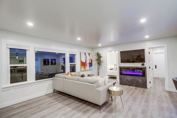 A modern living room with a white sofa, a small round table, and a large window.