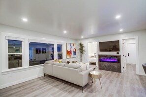 Un salon moderne avec un canapé blanc, une petite table ronde et une grande fenêtre.