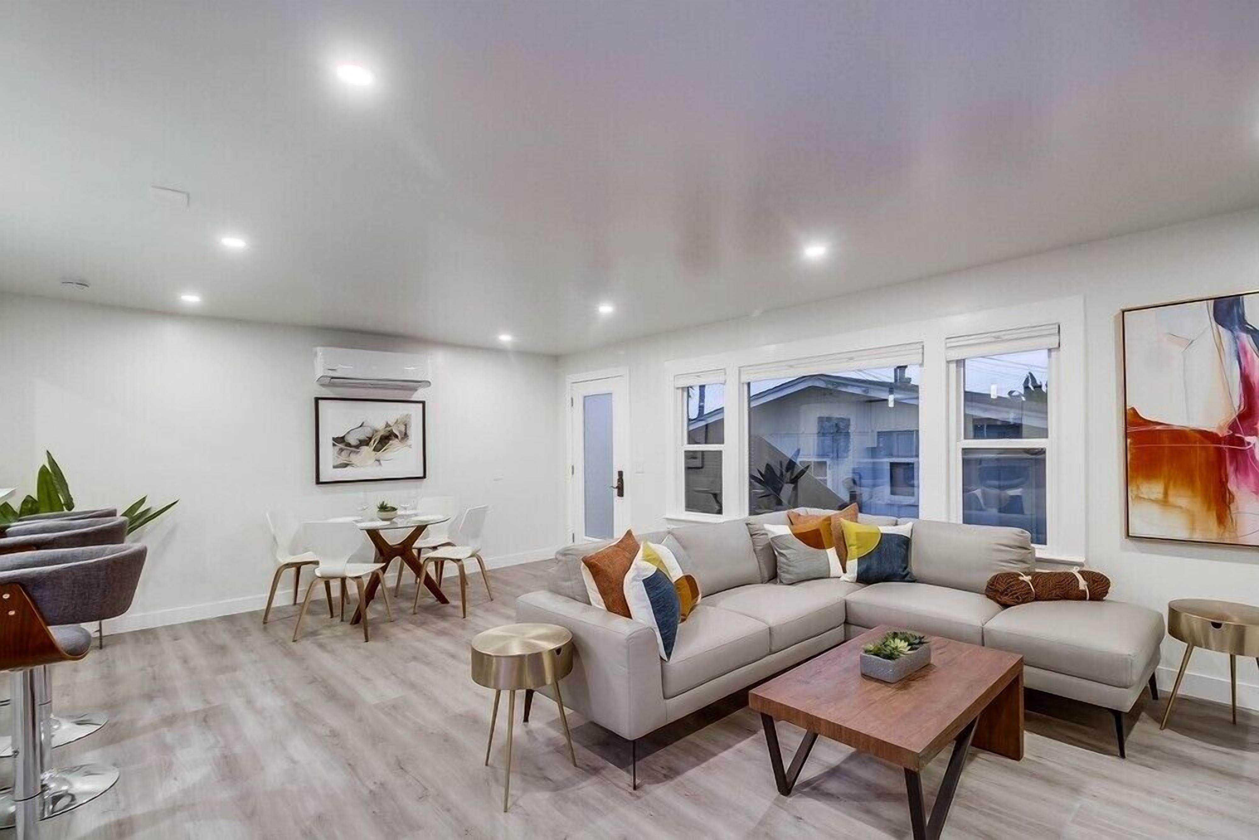 A modern living room with a sectional sofa, a coffee table, and a dining area with chairs and a small table.