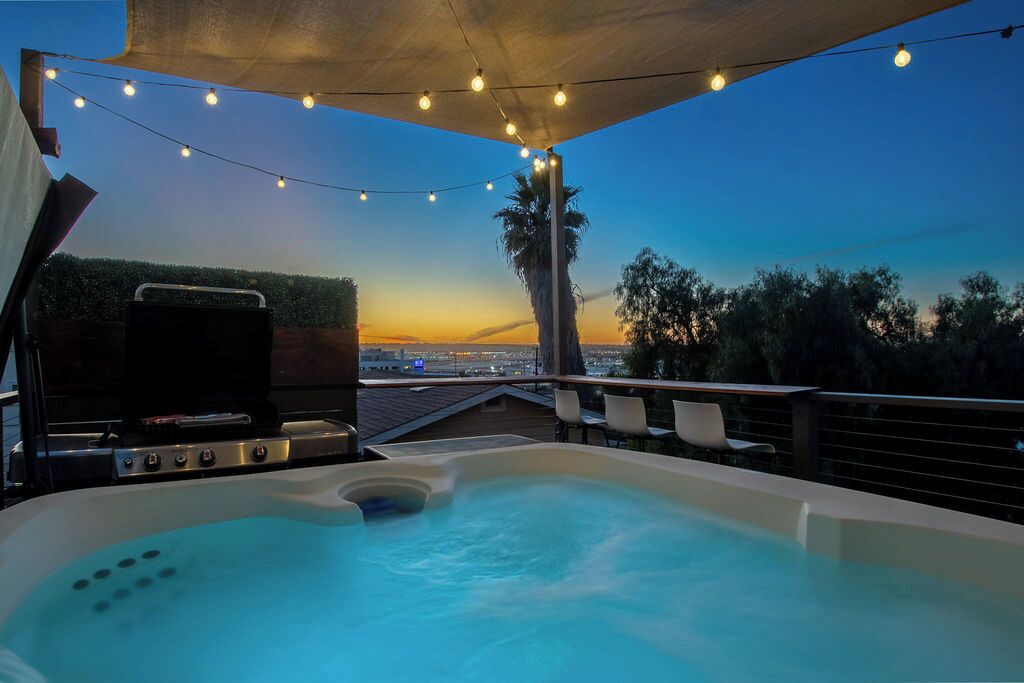 Een hottub met uitzicht op de stad, sfeerverlichting en een barbecue.
