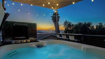 Een hottub met uitzicht op de stad, sfeerverlichting en een barbecue.
