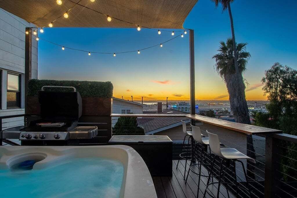 An outdoor patio with a hot tub, bar area, and string lights.