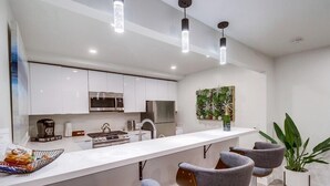 A modern kitchen with white cabinets, stainless steel appliances, and a central island with bar stools.