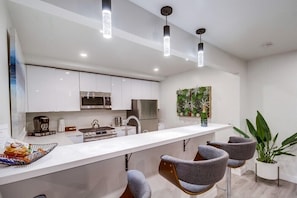A modern kitchen with white cabinets, stainless steel appliances, and a central island with bar stools.
