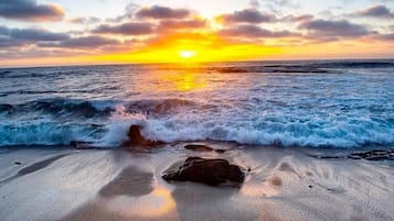 A beach with waves and a sunset.
