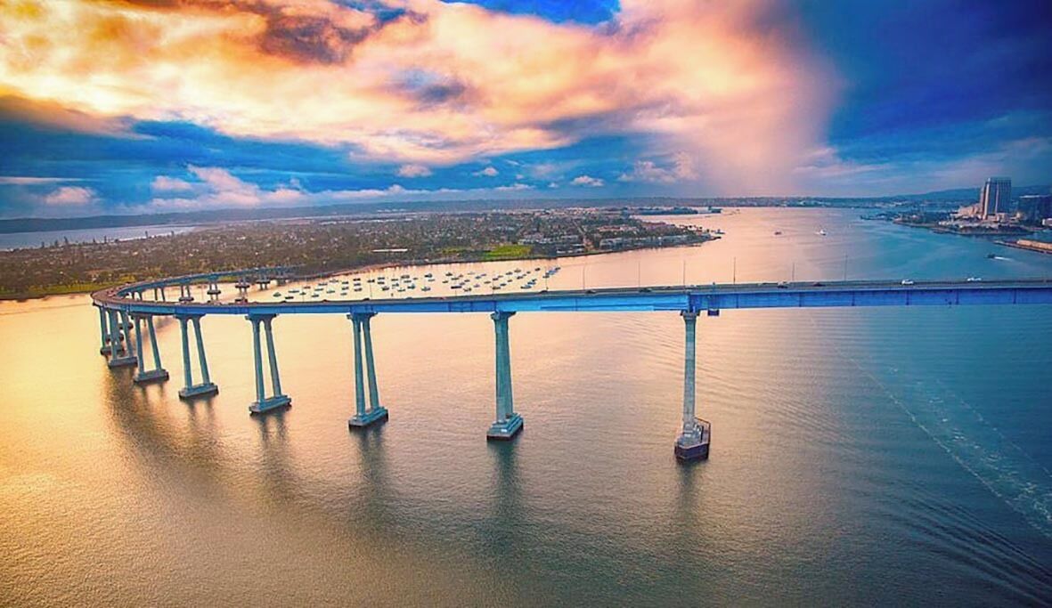 A bridge with multiple supports over a body of water, with a cityscape in the background.