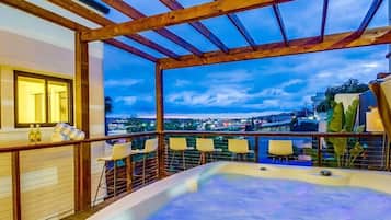 A rooftop terrace with a hot tub, seating area, and a view of the cityscape.