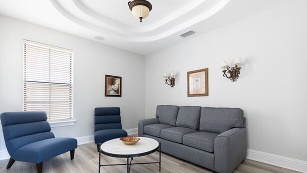 A living room with a grey sofa, two blue armchairs, a round coffee table, and a ceiling light fixture.