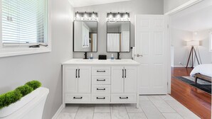 A modern bathroom with a white vanity, double mirrors, and a large mirror above the sink.