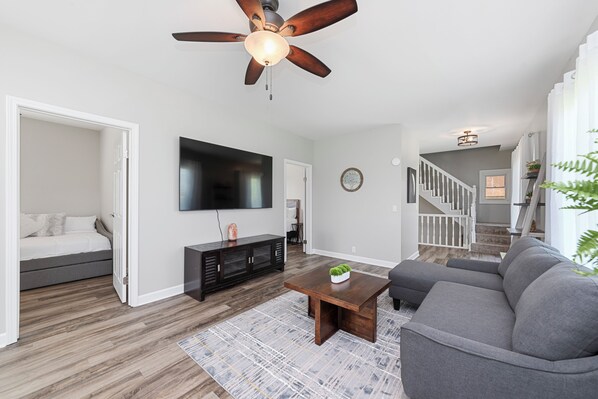 A modern living room with a grey sofa, a wooden coffee table, and a ceiling fan. - Spacious and family friendly getaway. 8 mins from Chicago Premium Outlet Mall.  (Aurora)