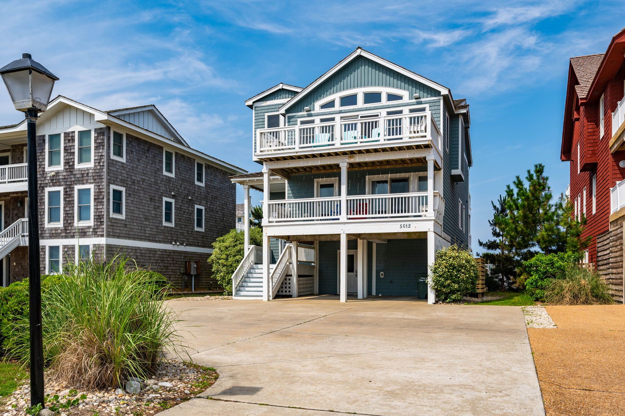 A multi-story residential building with a balcony on the second floor, a garage, and a driveway.
