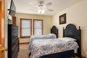 A bedroom with two beds, a ceiling fan, and a dresser.