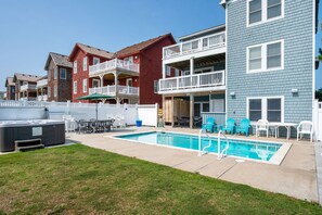 Zona residencial con piscina, mobiliario exterior y patio cercado.