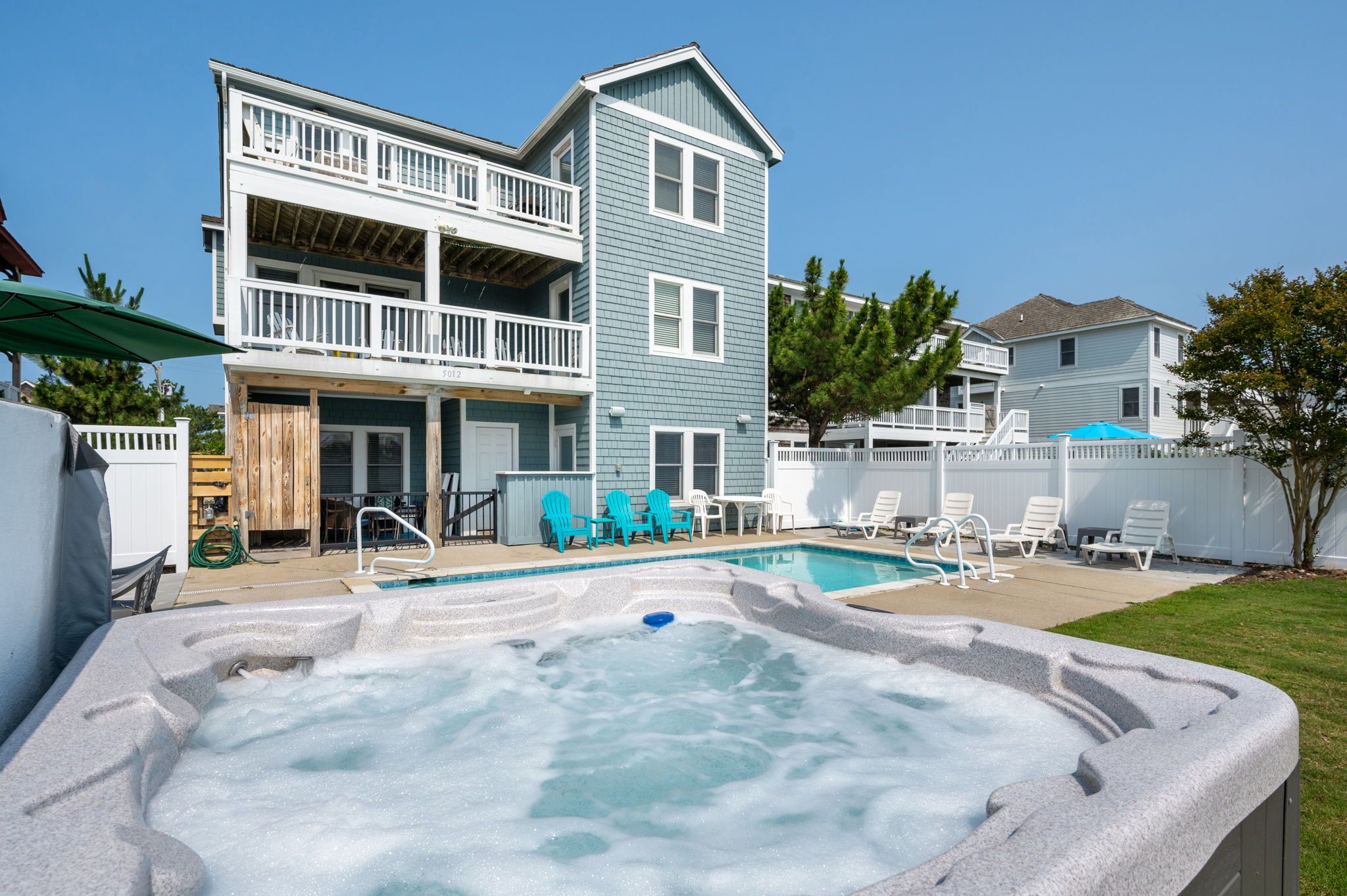 A two-story house with a backyard pool and hot tub.