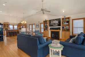 A spacious living room with a fireplace, a television mounted above it, and a dining area with a bar.