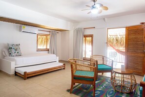 A room with a bed, two wicker chairs, a small table, a ceiling fan, and a view of the outside. - Hotel Isla del Sol  (Rosario Islands)