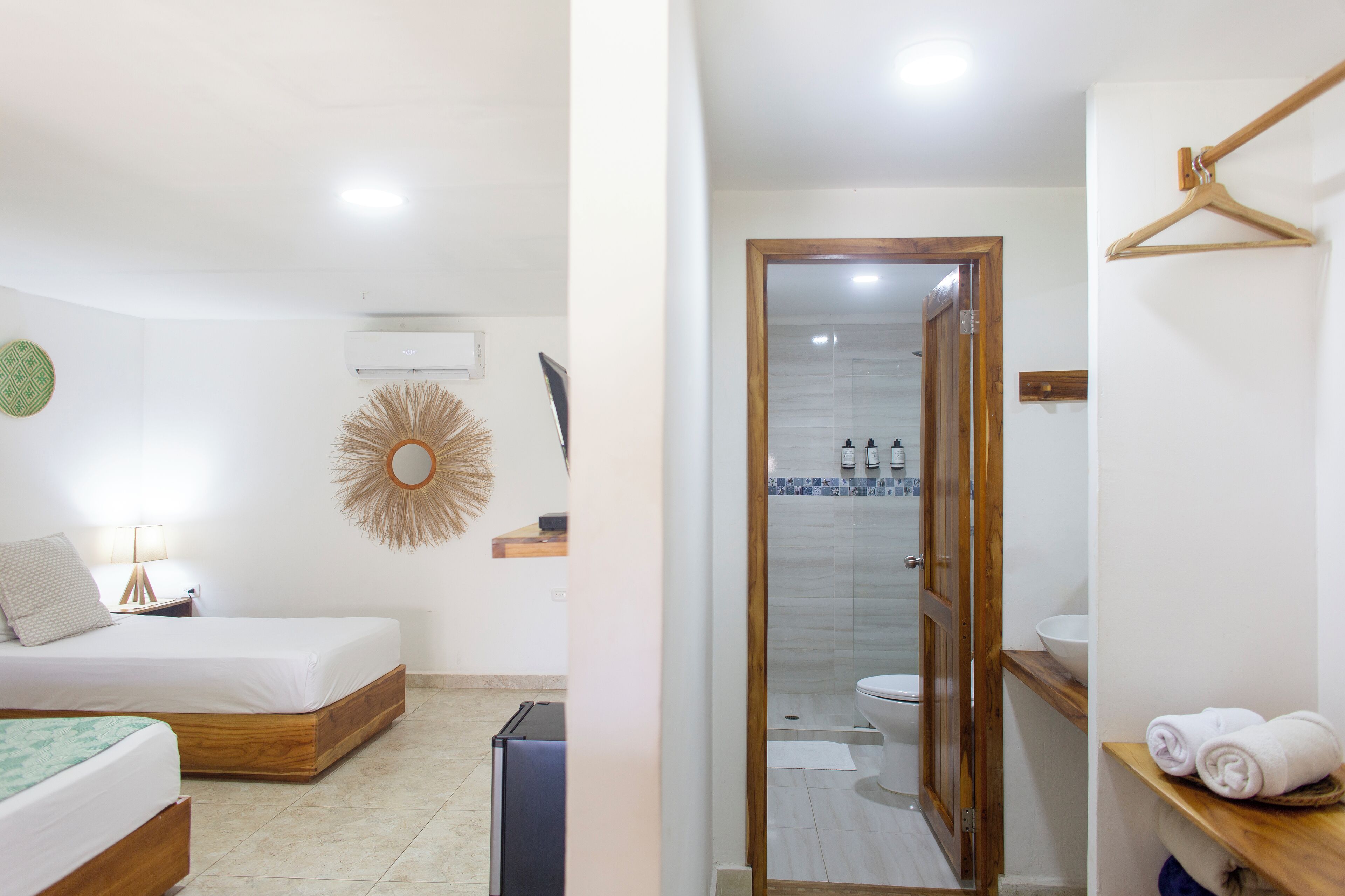 A bedroom with a bed, bedside table, lamp, and decorative mirror.