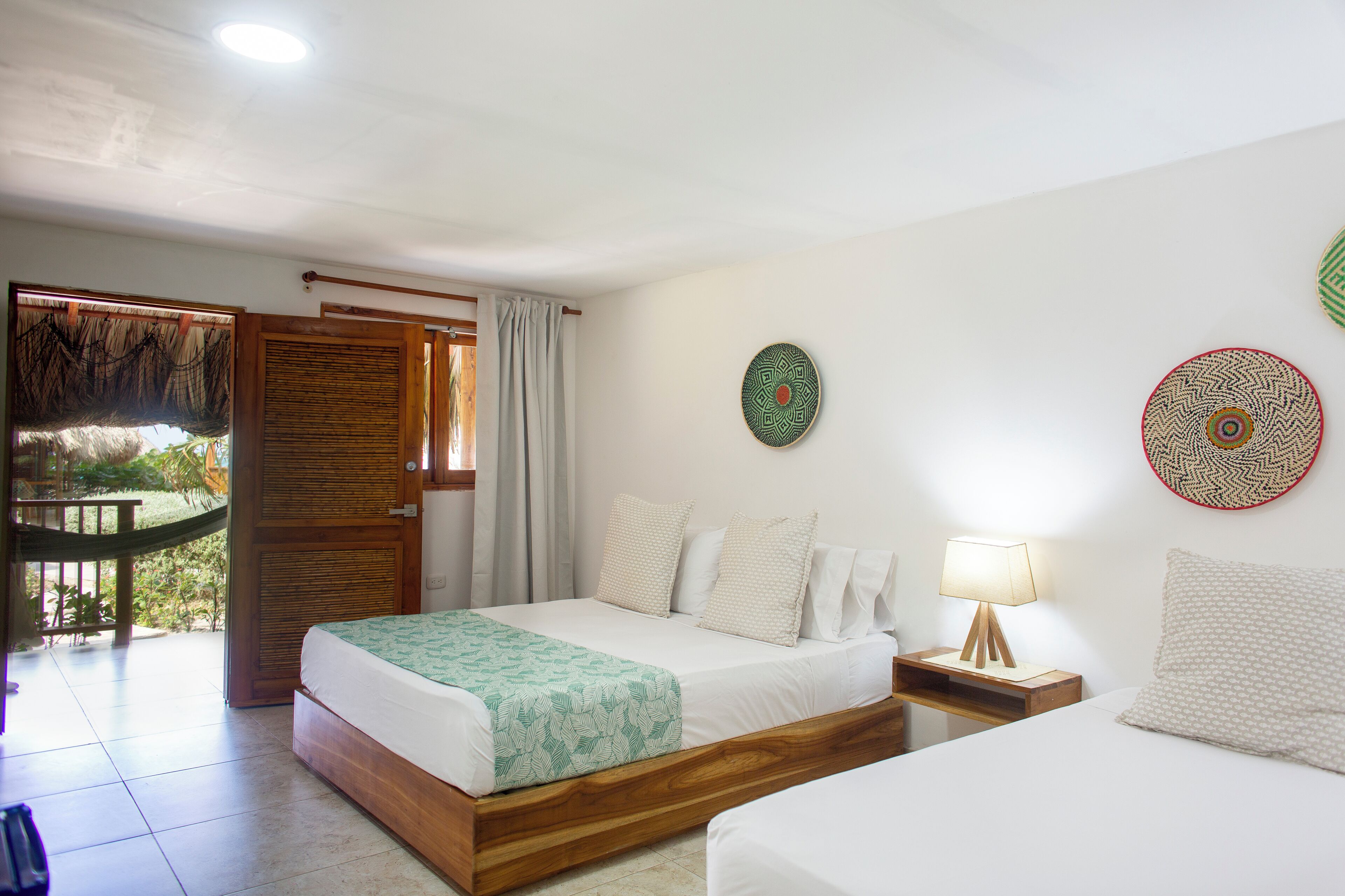 A hotel room with a bed, a nightstand, and a view of a garden.