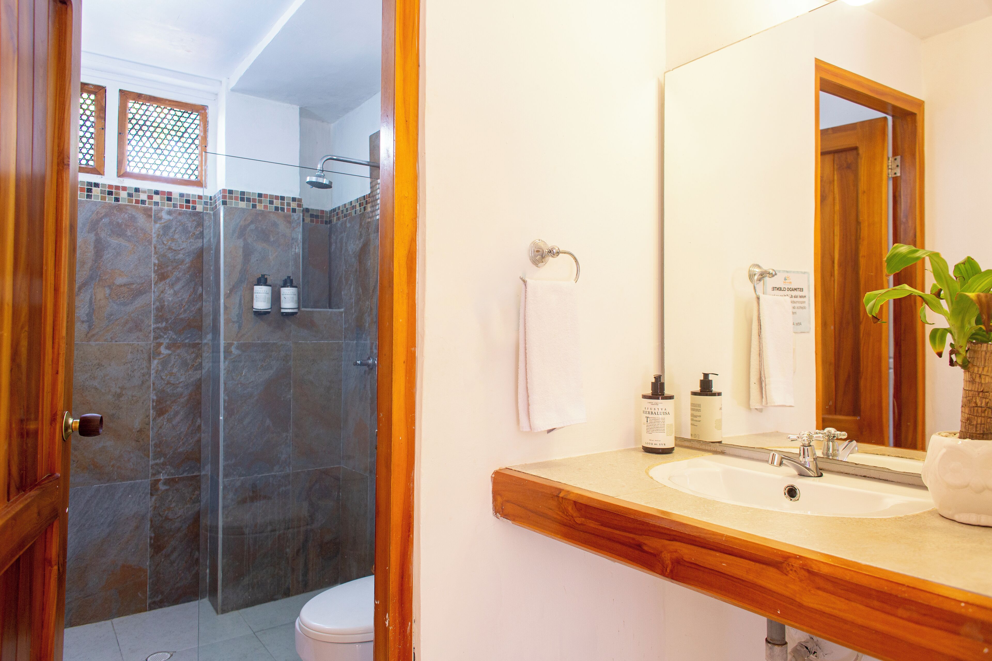 A bathroom with a shower, toilet, sink, and a mirror.