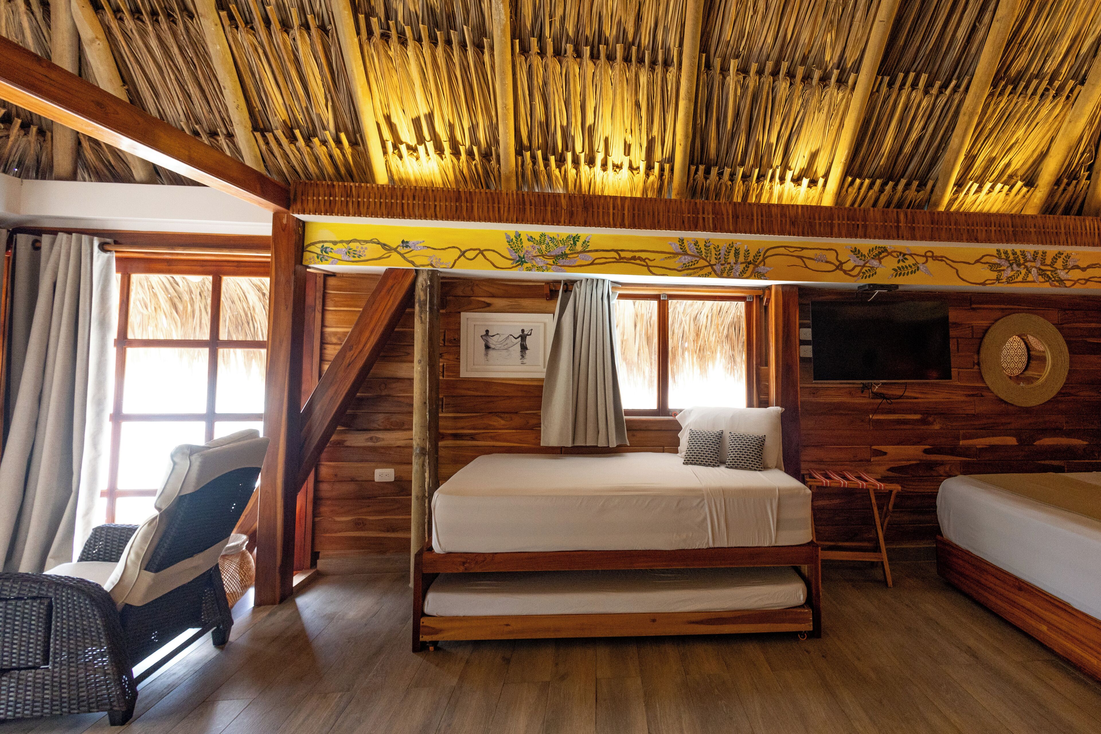 Habitación de cabaña de madera con una cama, una silla, una mesita y un televisor.