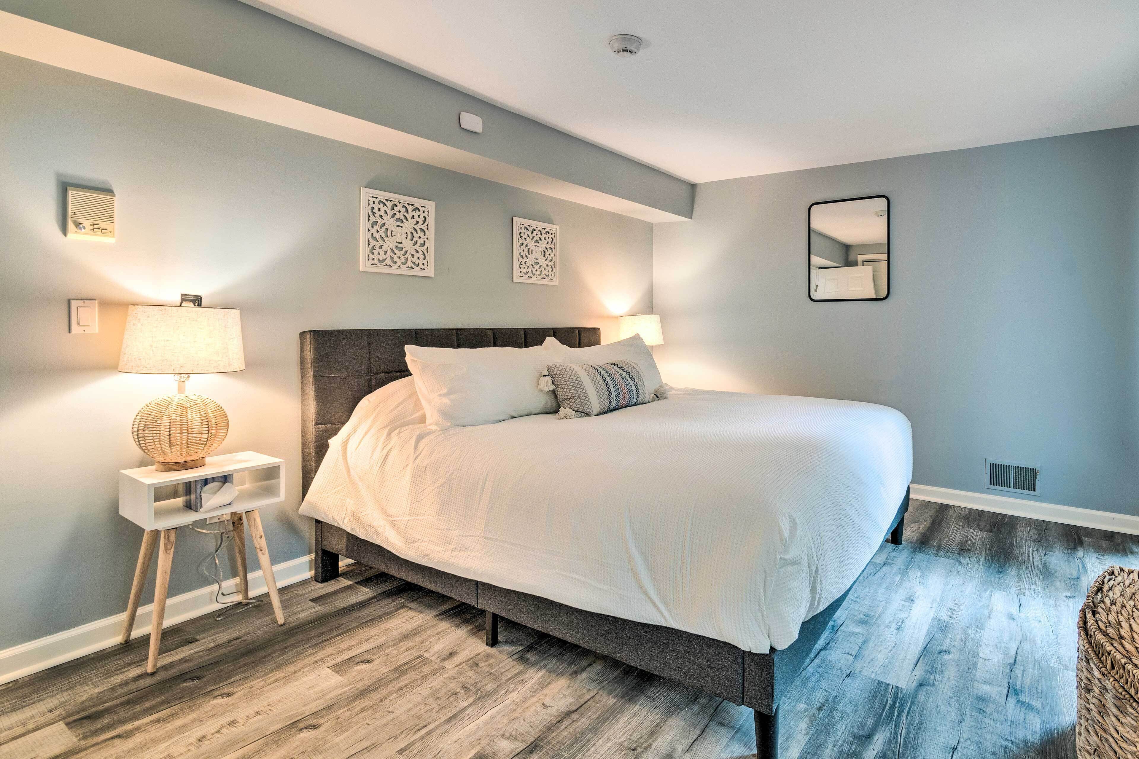 Une chambre moderne avec un grand lit, des lampes de chevet et des œuvres d’art décoratives au mur.