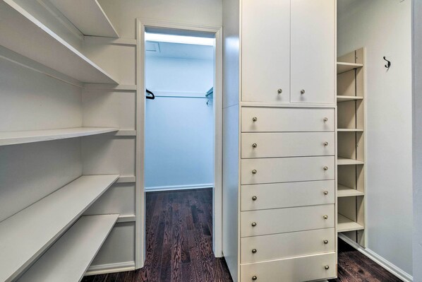 A walk-in closet with open shelving, a set of drawers, and a hanging rod.