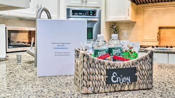 A kitchen counter with a woven basket containing snacks and a sign with contact information.