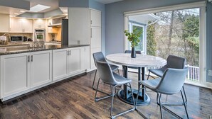 A modern kitchen with white cabinets, a granite countertop, and a dining area with a round table and chairs.