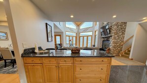 A spacious kitchen with granite countertops, wooden cabinets, and a large island.