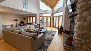 A spacious living room with a large gray sofa, a coffee table, and a stone fireplace.