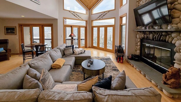 A spacious living room with a large sectional sofa, a fireplace, and a stone accent wall.