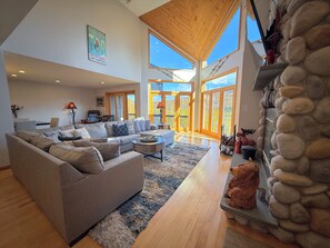 A spacious living room with a large sectional sofa, a coffee table, and a stone fireplace. - C16 Renovated Ski-in/Out luxury home in Bretton Woods; Great Views. Pool/gym passes! (Bretton Woods)
