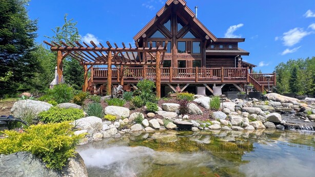 A lodge with a wooden deck and a pond with fish. - WM dream home in National Forest; AC, swimspa, beach, massage chair, 2 min from ski area! (Bretton Woods)